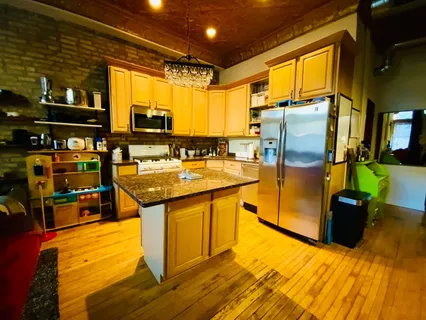 a kitchen with stainless steel appliances granite countertop a refrigerator a stove and a dining table with wooden floor