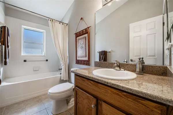 a bathroom with a granite countertop sink toilet mirror and bathtub