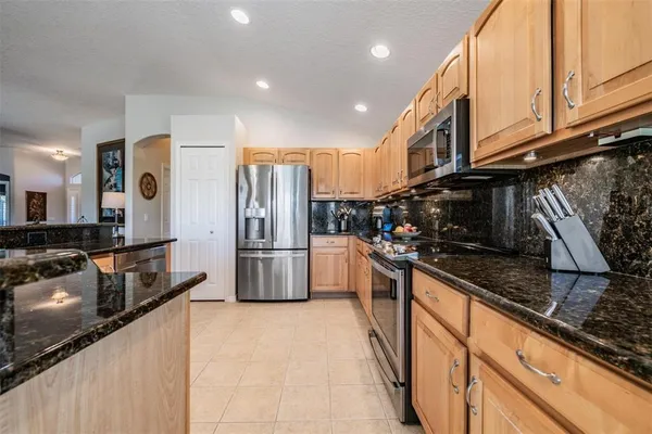 a kitchen with stainless steel appliances granite countertop a refrigerator a stove and a sink