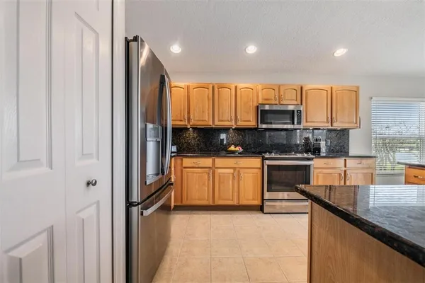 a kitchen with kitchen island granite countertop a stove top oven a sink a counter space and cabinets