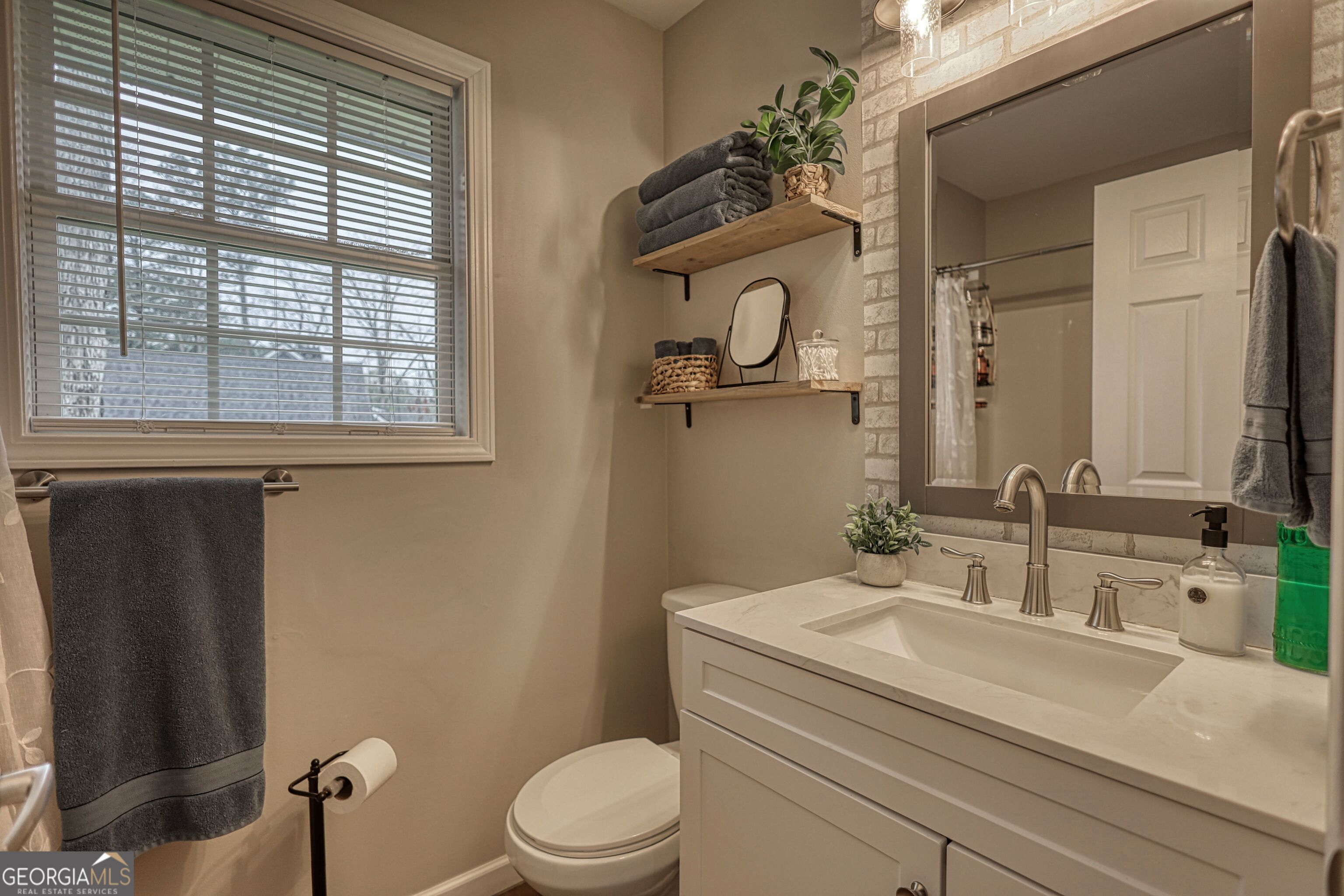 30 Waters Street Monticello, GA 31064 - Photo 26 of 40 a bathroom with a granite countertop toilet a sink a mirror and a window