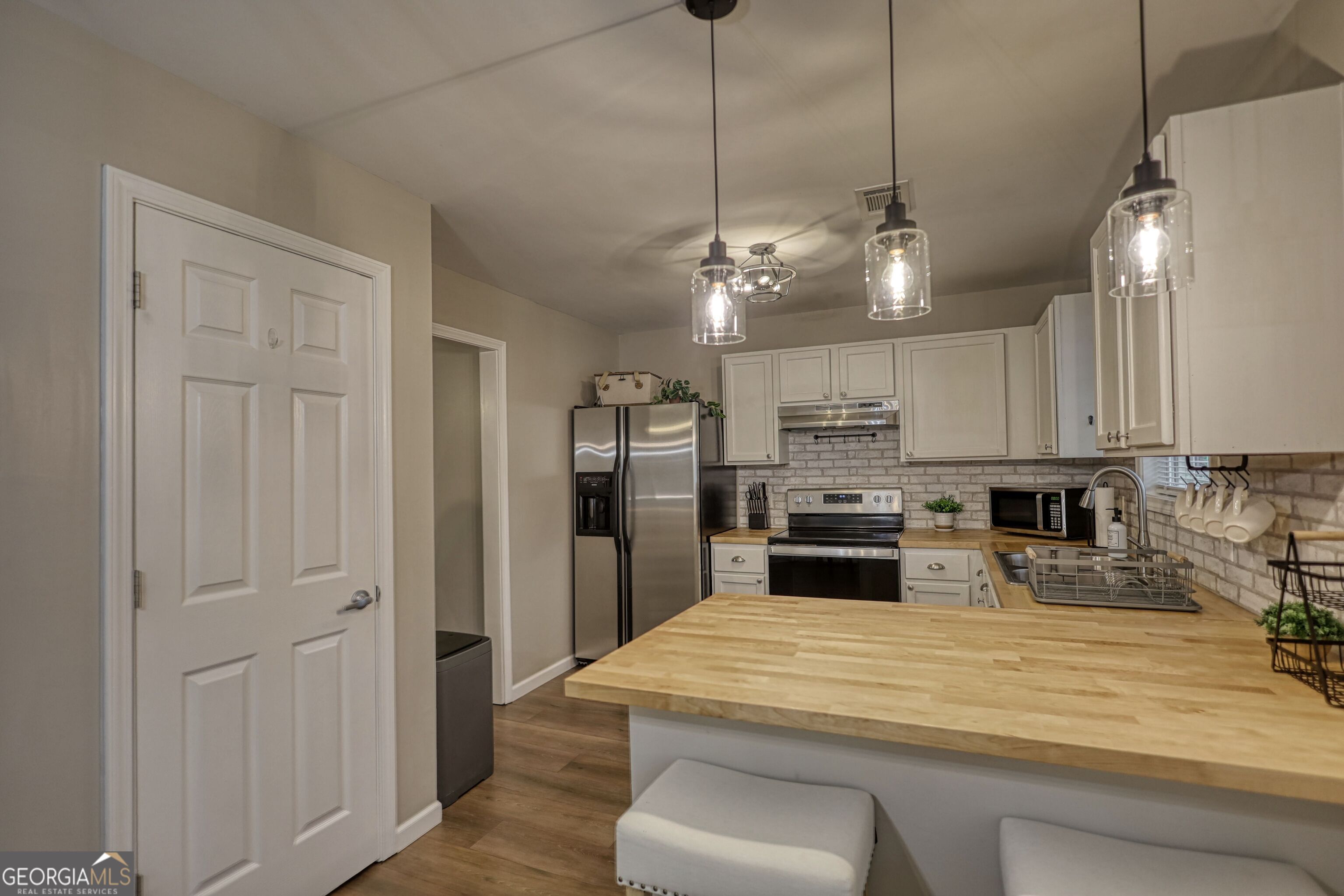 30 Waters Street Monticello, GA 31064 - Photo 10 of 40 a kitchen with stainless steel appliances kitchen island granite countertop a refrigerator a stove and a sink with wooden floor