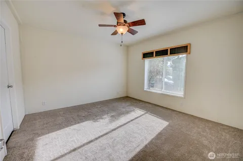 an empty room with ceiling fan and window