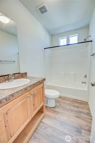 a bathroom with a granite countertop sink a toilet a mirror and shower