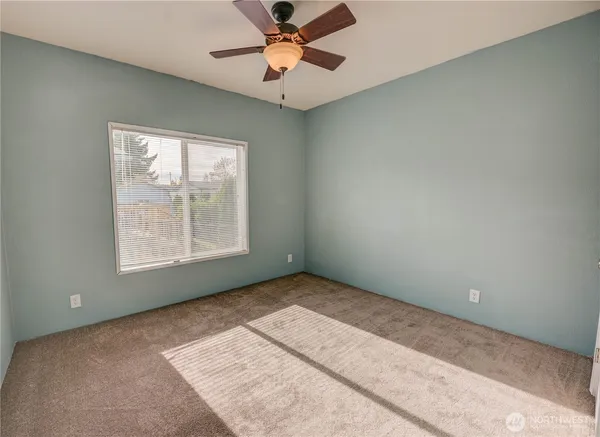 an empty room with windows and fan