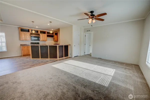 a view of a livingroom with a ceiling fan & kitchen view