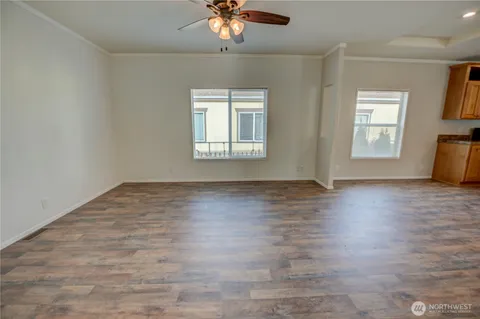 an empty room with wooden floor chandelier fan and windows