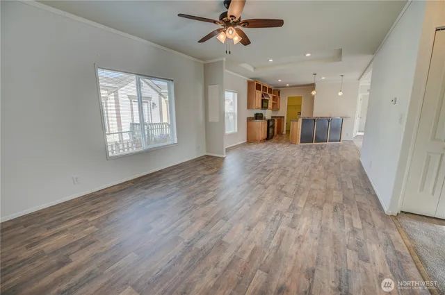 an empty room with wooden floor ceiling fan and windows