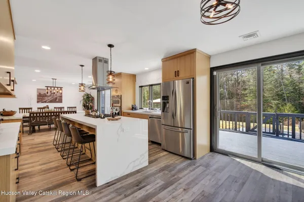 a kitchen with stainless steel appliances a refrigerator a stove top oven and a dining table