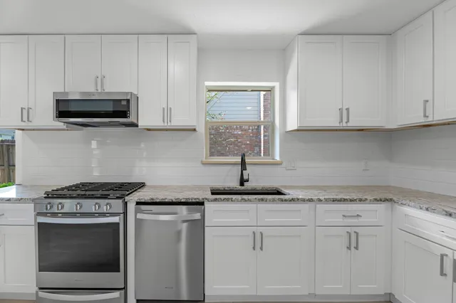 a kitchen with granite countertop white cabinets and white appliances