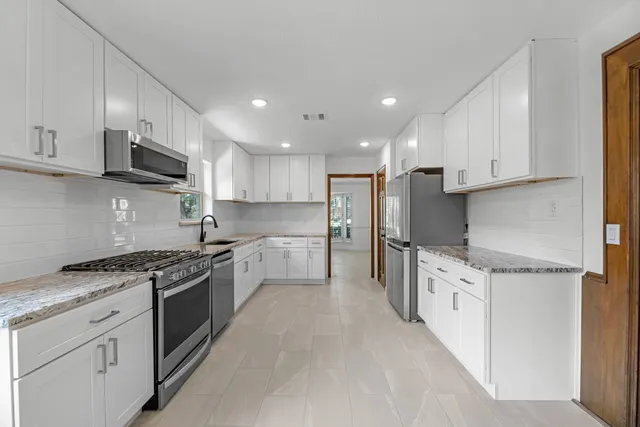 a kitchen with stainless steel appliances granite countertop a stove top oven a sink and a refrigerator
