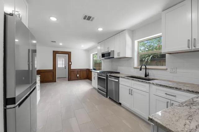 a kitchen with granite countertop a sink stainless steel appliances and cabinets