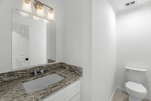 a bathroom with a granite countertop sink and a toilet