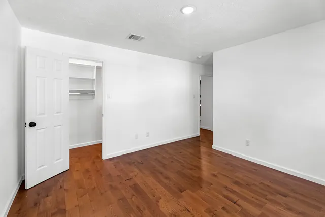 an empty room with wooden floor & windows