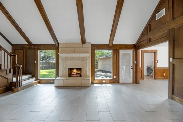 a view of a entryway door an an empty room and fire place