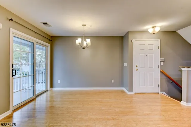 a view of an empty room with chandelier fan and fire place