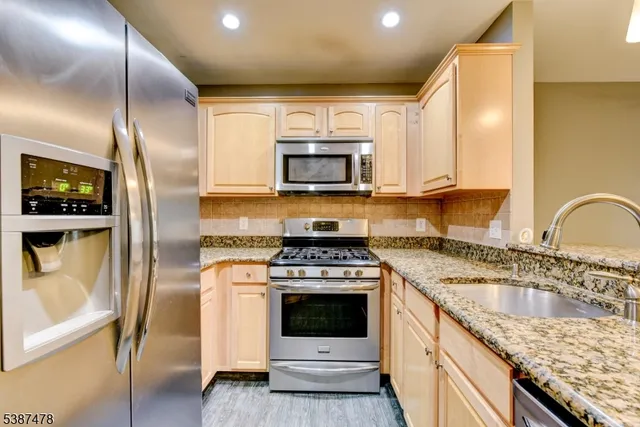a kitchen with granite countertop a sink stainless steel appliances and cabinets