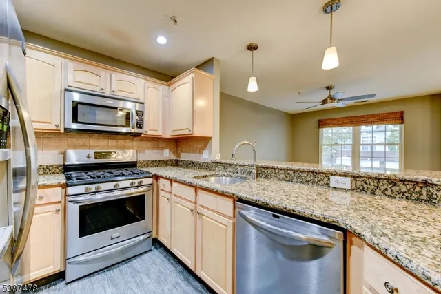 a kitchen with granite countertop a sink stainless steel appliances and cabinets