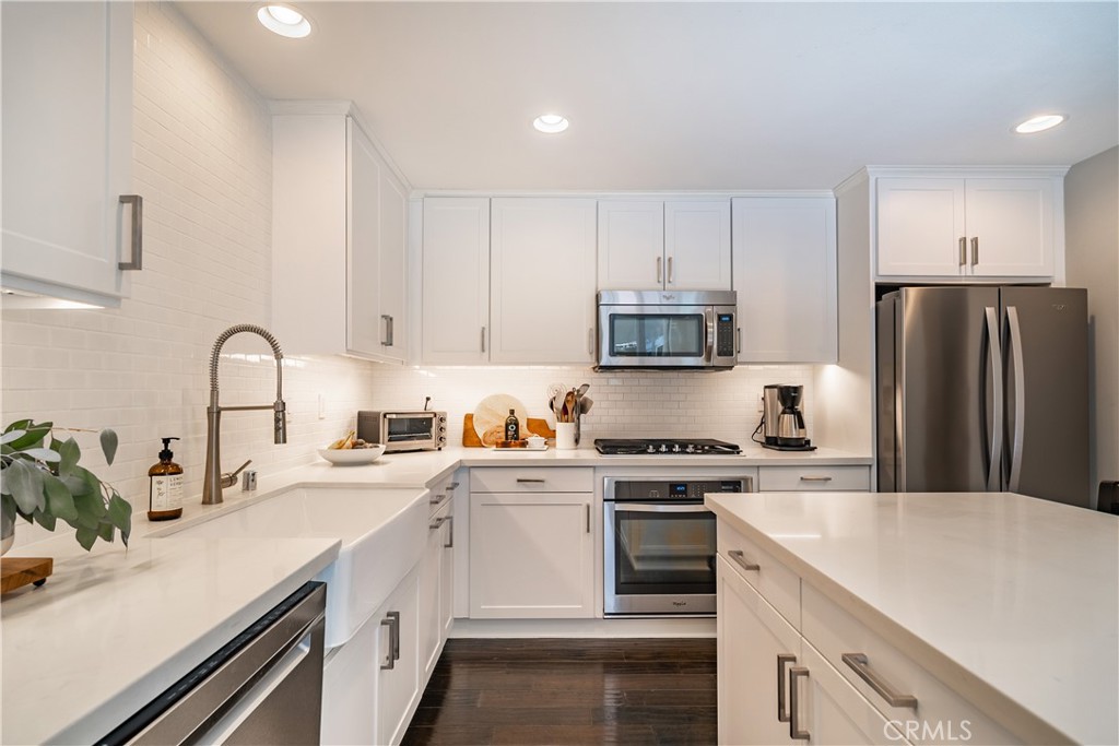 a kitchen with a sink white cabinets and stainless steel appliances