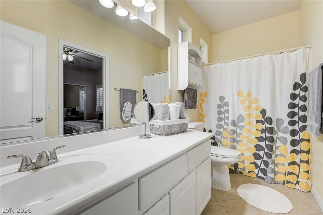 1604 Cattle Ranch Place Henderson, NV 89002 - Photo 53 of 99 A pristine bathroom featuring a vanity with a white countertop, modern fixtures, and a shower with a vibrant botanical curtain.