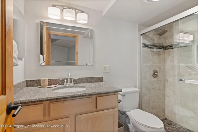 a bathroom with a granite countertop toilet a sink and a mirror