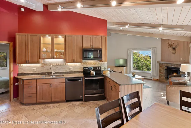 a kitchen with stainless steel appliances granite countertop a stove top oven a sink dishwasher and a refrigerator with wooden floor