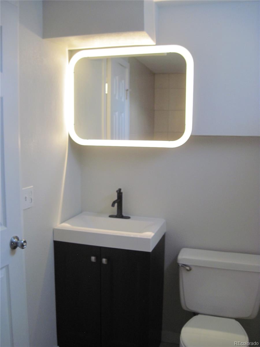 1014 Alexander Road Colorado Springs, CO 80909 - Photo 27 of 44 a bathroom with a toilet sink and mirror