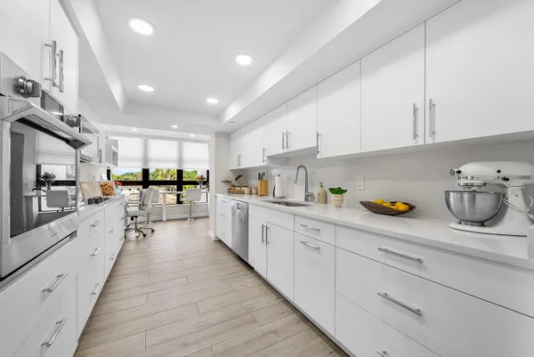 a large white kitchen with lots of counter space wooden floor and appliances