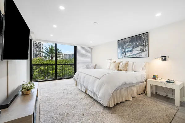 a spacious bedroom with a large bed and a flat tv screen