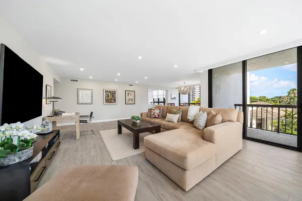 a living room with furniture a flat screen tv and a floor to ceiling window