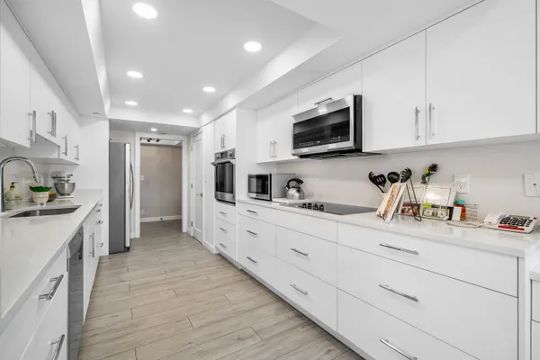 a kitchen with stainless steel appliances granite countertop white cabinets a sink dishwasher and a refrigerator