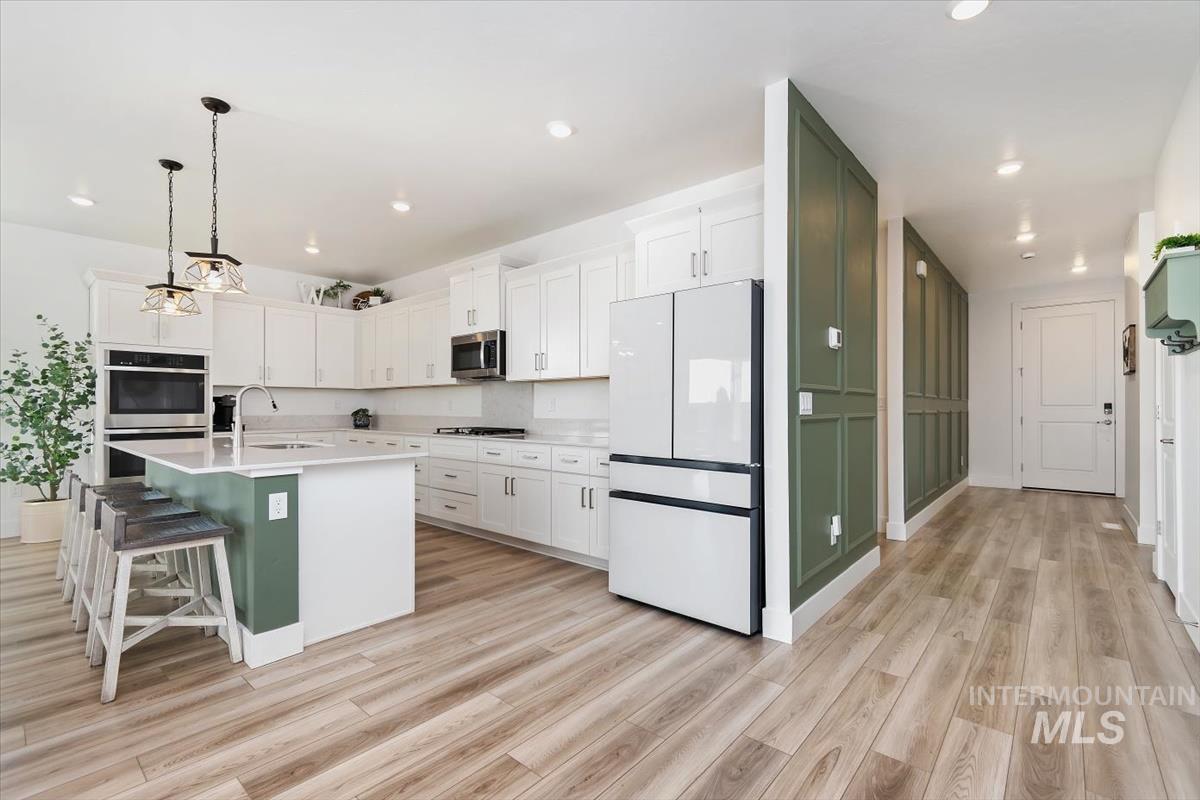 14361 Fractus Drive Caldwell, ID 83607 - Photo 11 of 50 Kitchen with white cabinetry, appliances with stainless steel finishes, a breakfast bar area, decorative light fixtures, and a center island with sink