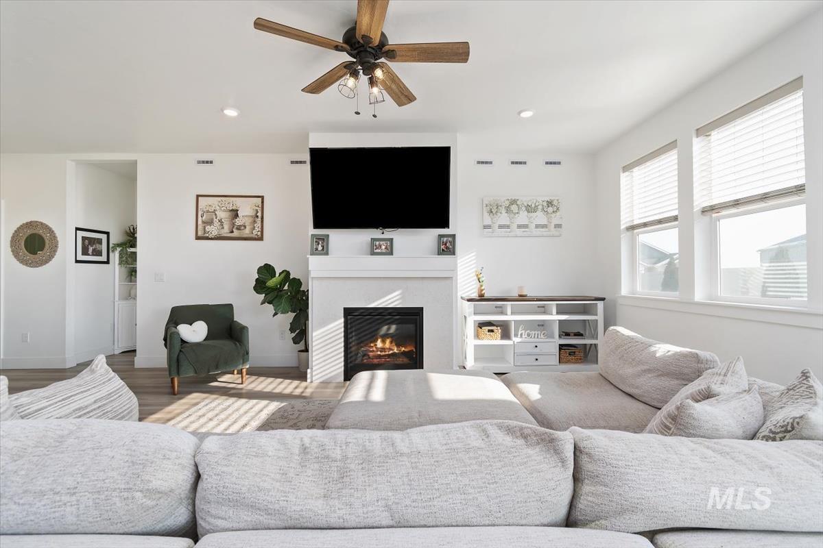 14361 Fractus Drive Caldwell, ID 83607 - Photo 4 of 50 Living room with a glass covered fireplace, a ceiling fan, wood finished floors, and recessed lighting