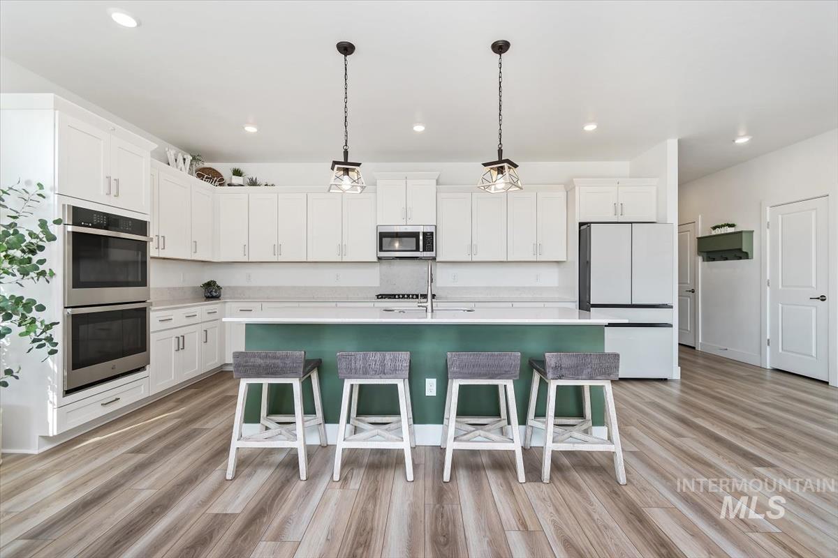 14361 Fractus Drive Caldwell, ID 83607 - Photo 8 of 50 Kitchen featuring white cabinetry, stainless steel appliances, hanging light fixtures, a center island with sink, and recessed lighting