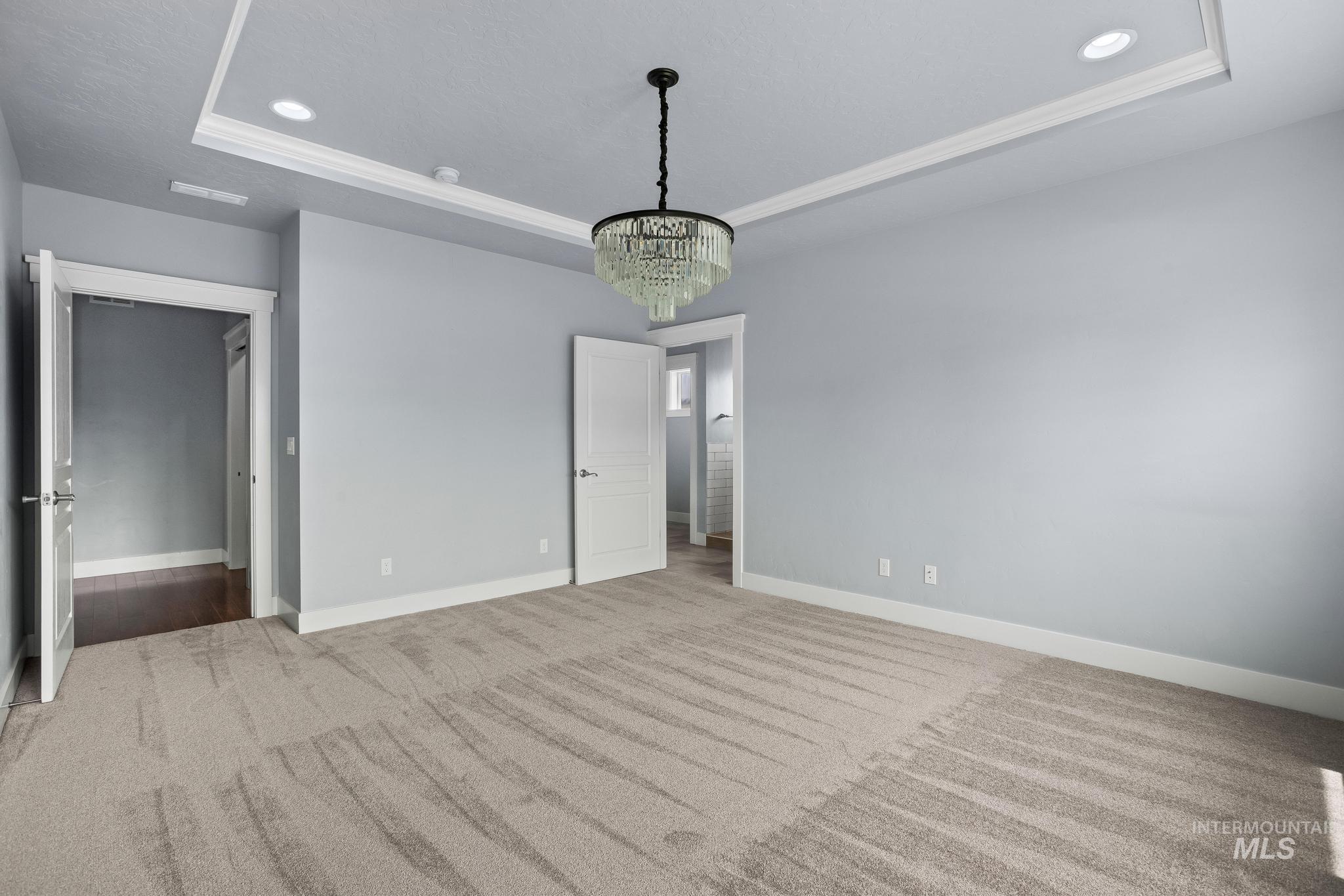 2681 East Rhyolite Court Nampa, ID 83686 - Photo 25 of 48 Spacious room featuring tray ceiling, recessed lighting, a modern chandelier, light gray walls, and plush carpeting