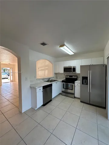 a kitchen with granite countertop a refrigerator and a stove top oven