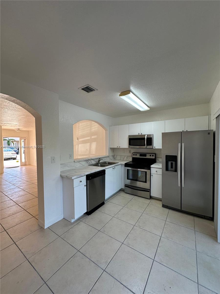 13713 Southwest 171st Lane Miami, FL 33177 - Photo 2 of 18 a kitchen with granite countertop a refrigerator and a stove top oven