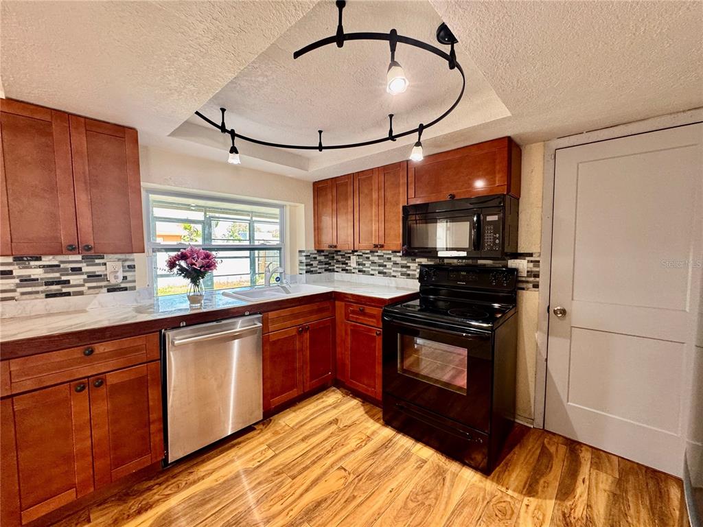 3902 Glissade Drive New Port Richey, FL 34652 - Photo 9 of 26 a kitchen with stainless steel appliances granite countertop a stove sink and cabinets