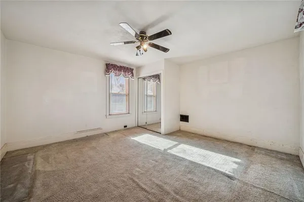a view of an empty room with closet and a chandelier fan