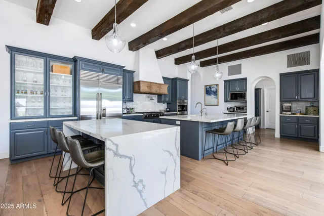 a kitchen with stainless steel appliances kitchen island granite countertop a table chairs sink and cabinets