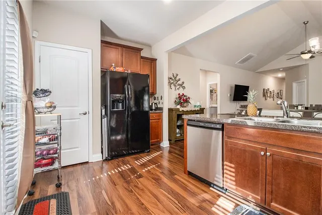a kitchen with stainless steel appliances kitchen island granite countertop a refrigerator and a sink