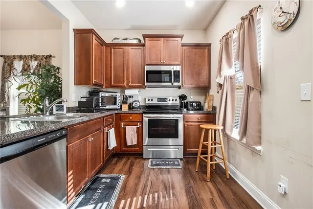 a kitchen with granite countertop a stove a sink and a microwave