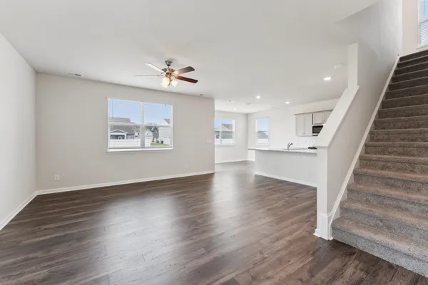 a view of an empty room with wooden floor and a ceiling fan