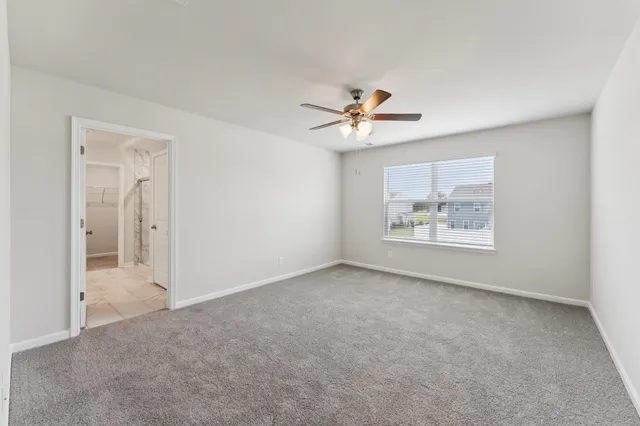 an empty room with windows and ceiling fan