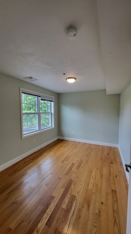 277 Pawtucket Street, Unit 2C Lowell, MA 01854 - Photo 13 of 16 an empty room with wooden floor and windows