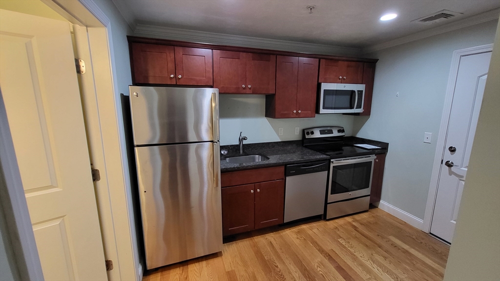 277 Pawtucket Street, Unit 2C Lowell, MA 01854 - Photo 3 of 16 a kitchen with a refrigerator sink and cabinets