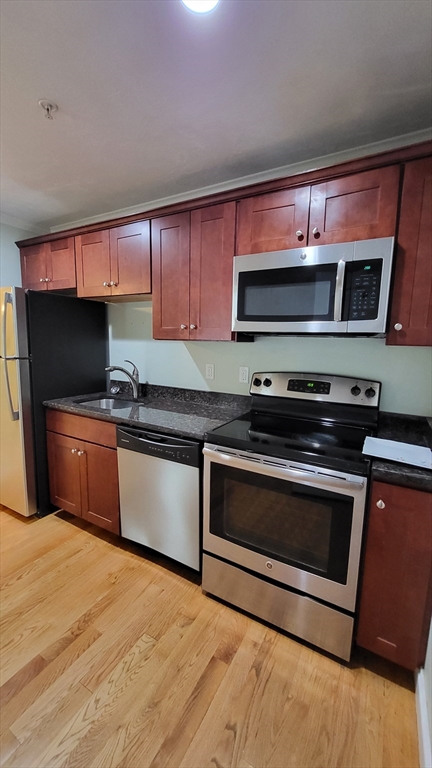 277 Pawtucket Street, Unit 2C Lowell, MA 01854 - Photo 5 of 16 a kitchen with stainless steel appliances kitchen island granite countertop a sink and a stove