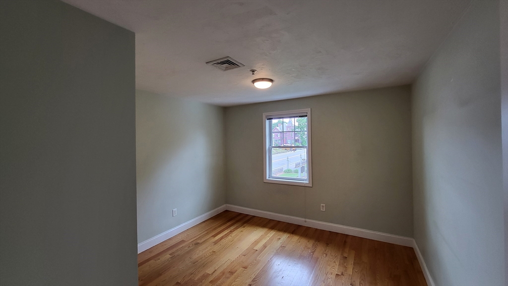 277 Pawtucket Street, Unit 2C Lowell, MA 01854 - Photo 9 of 16 an empty room with wooden floor and windows