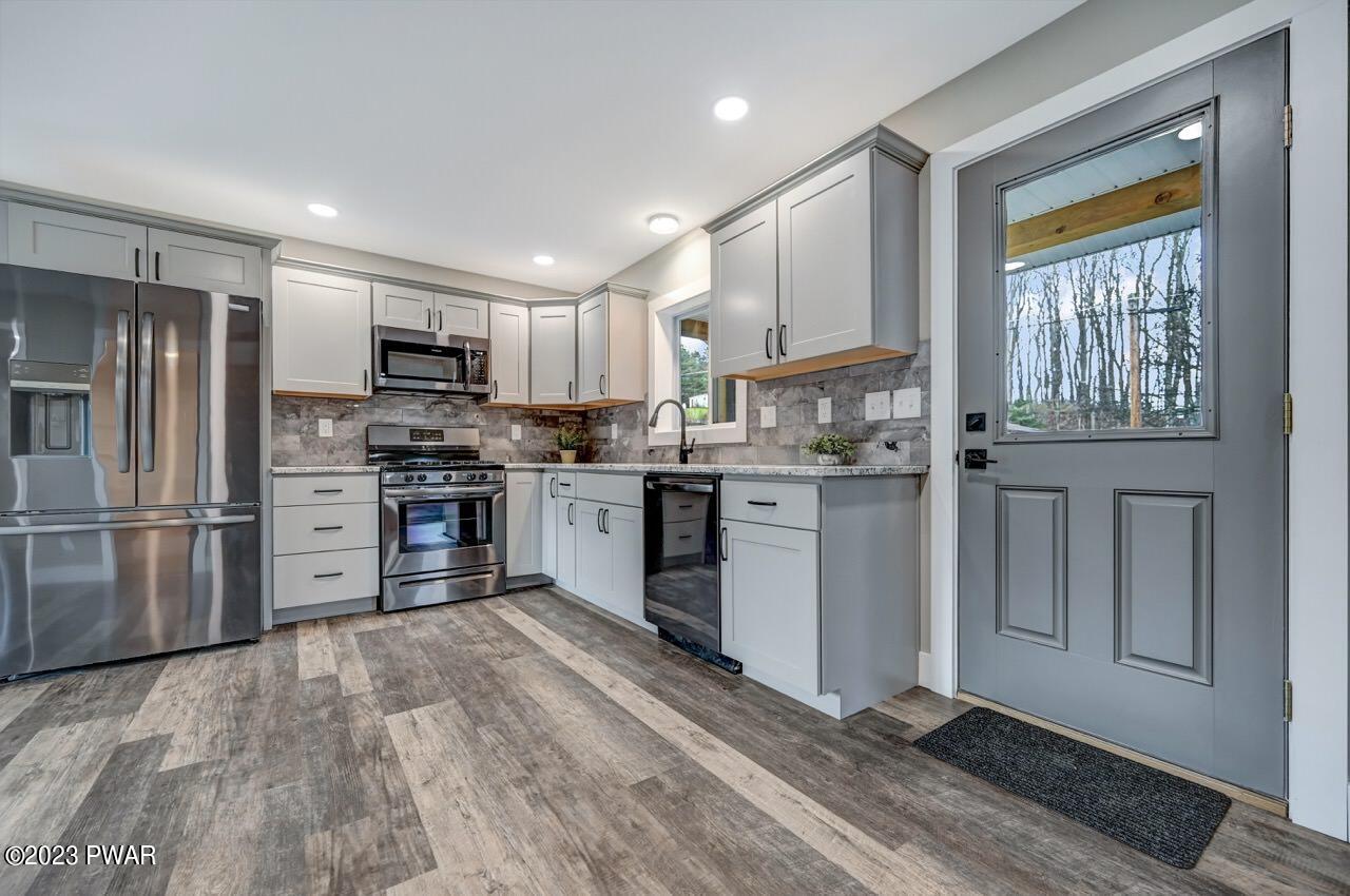16 Pond Road Moscow, PA 18444 - Photo 10 of 55 a kitchen with stainless steel appliances granite countertop a refrigerator oven a sink dishwasher and white cabinets with wooden floor