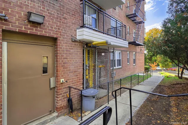 a view of a brick house with a bench and potted plants